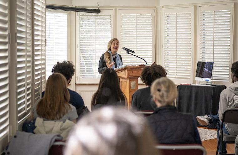 Naomi Shihab Nye speaks to a room full of students from a podium